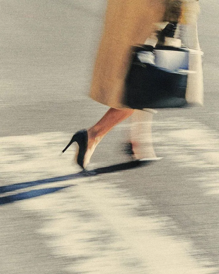 A businesswoman in heels walking past with a handbag, in motion blur